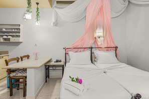 A neatly arranged bedroom with a bed, bedside table, and a small desk with a chair. - Golden Bay Apartments-garden Haven (Hersonissos)