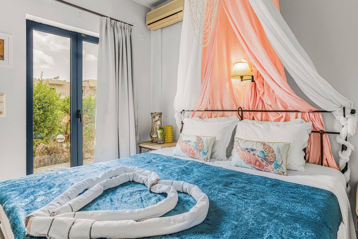 Un dormitorio con cama, dosel, mesita de noche y vistas al exterior.