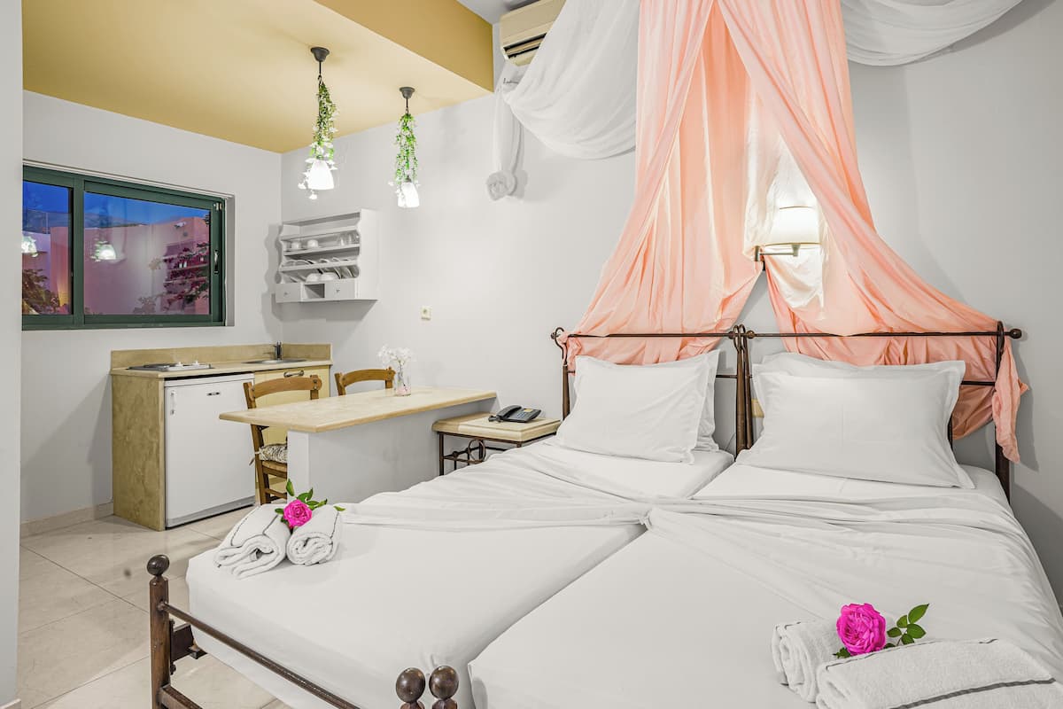Una habitación de hotel con cama, escritorio, silla, kitchenette pequeño y ventana.