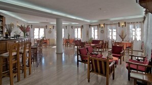 Un amplio vestíbulo de hotel con mobiliario de madera, una columna central y grandes ventanales.