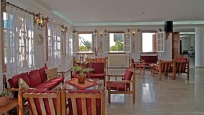 Una habitación amplia con un gran ventanal, un sofá, sillas y una mesa con una planta.