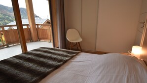 A bedroom with a bed, a chair, and a view of the outdoors.