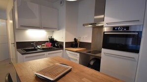 A modern kitchen with white cabinets, a wooden countertop, a built-in oven, and a coffee maker.