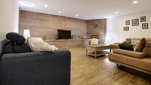 Una sala de estar moderna con una pared de acento de madera, un televisor de pantalla plana, un sofá, una mesa de centro y una chimenea.