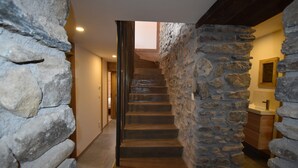 Una escalera de piedra que lleva a un baño con techo de madera y pared de piedra.