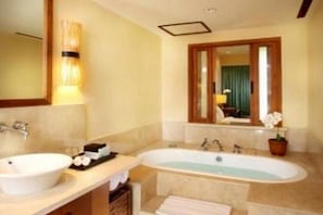 Un baño con lavamanos, bañera y espejo.