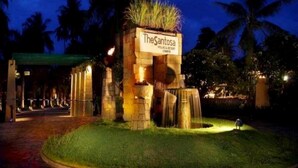 The Santosa Villas & Resort entrance at night with illuminated signage, a water feature, and palm trees in the background. - Santosa Villas & Resort (Senggigi)
