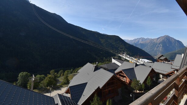A mountainous landscape with a ski lift and wooden cabins with sloped roofs.