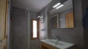 Ein Badezimmer mit Dusche, Waschbecken und Spiegel.