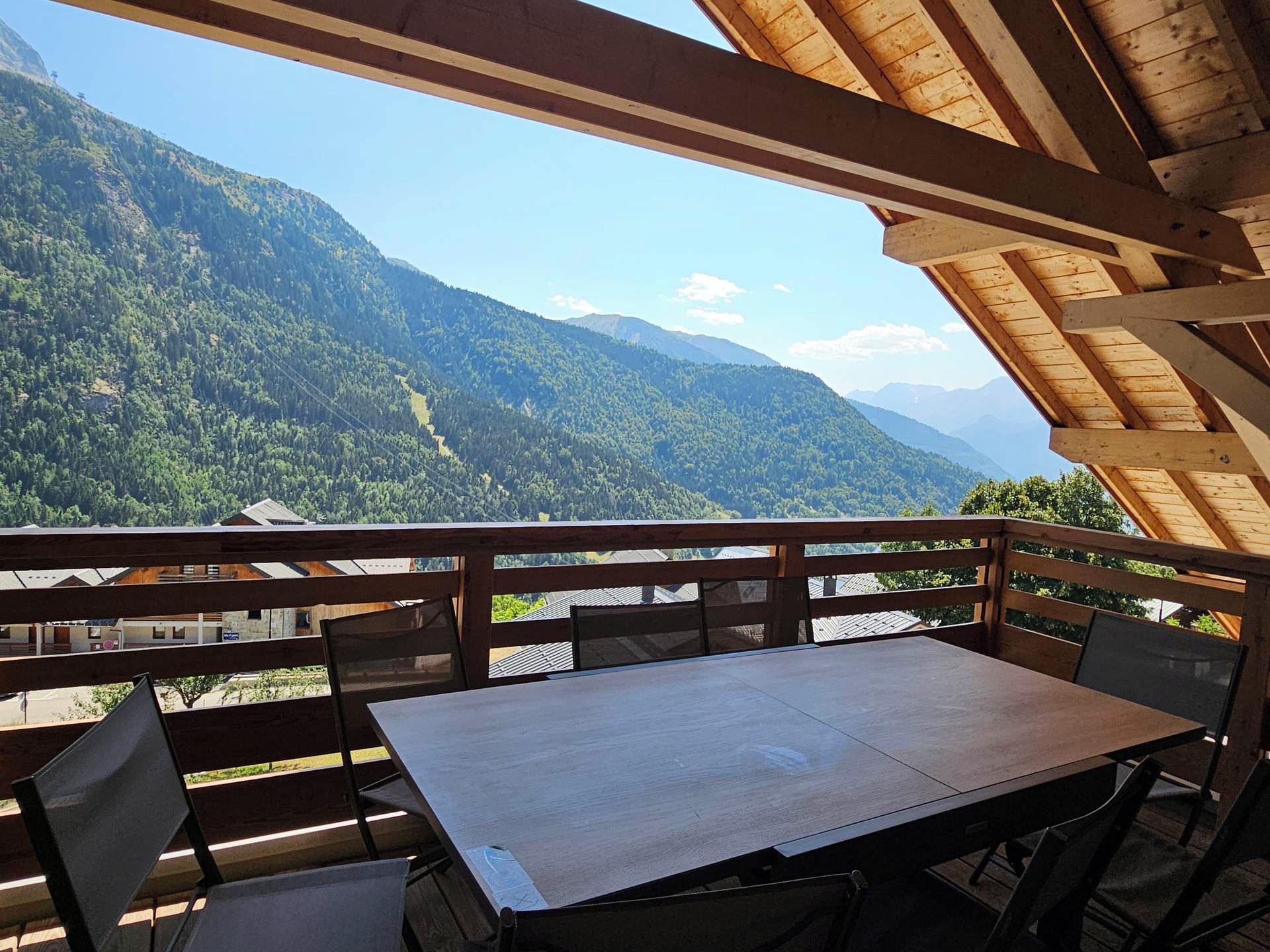 A wooden deck with a table and chairs overlooking a mountainous landscape.