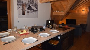 Ein Essbereich mit einem langen Holztisch, gedeckt für eine Mahlzeit, einem Gemälde mit einer verschneiten Berglandschaft und einer gemütlichen Holzzahlung.