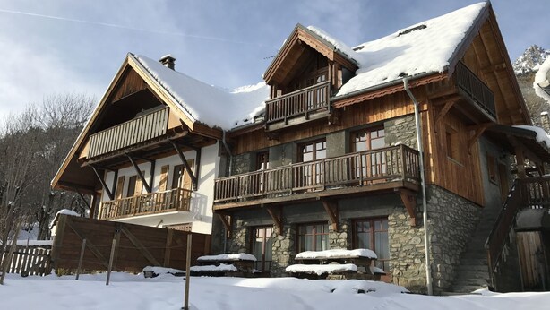 A chalet-style hotel with a wooden exterior, stone accents, and multiple balconies.