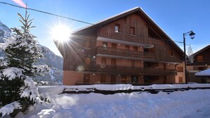 Un bâtiment en bois à plusieurs étages, doté de balcons, entouré d’un paysage enneigé et d’arbres.
