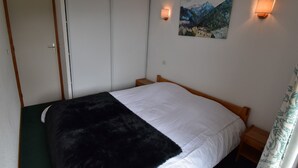Une chambre à coucher avec un lit, un tableau et deux lampes fixées au mur.