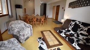 Una sala de estar acogedora con sofá, mesa de comedor con sillas, una mesa de centro y chimenea.