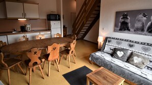 Un espacio de estar acogedor con una mesa de madera, sillas, un sofá y una escalera.