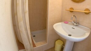 Un bany amb dutxa, un lavabo, un mirall i una barra de tovalloles.