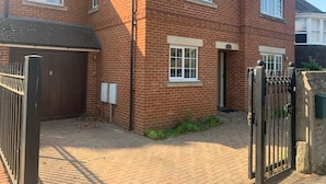 A two-story brick house with a front garage, a gated driveway, and a small garden area. - 3 bedroom house in Reading (Reading)