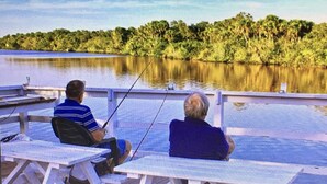 Two people fishing at a lakeside dock with picnic tables and a railing. - Perfect place to call a Timeout! 3 beaches within 15 minutes! With a pool! (Venice)