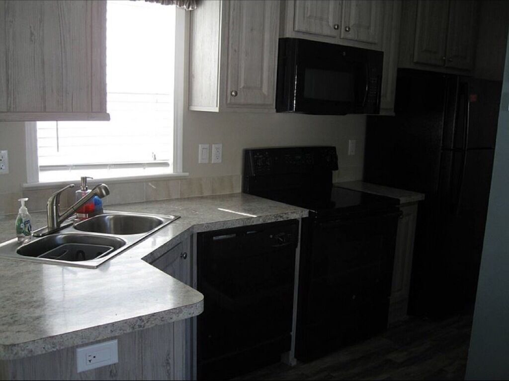 A kitchen with a double sink, a microwave, a dishwasher, and a refrigerator.