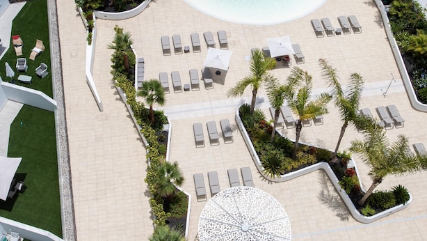 An aerial view of a resort with a pool, sun loungers, and a circular seating area. - Spacious ground floor apartment with large terrace and sea views in Costa Adeje (Adeje)