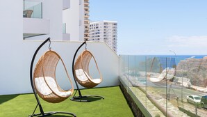 A balcony with two wicker chairs, a view of the sea, and a modern building in the background. - Spacious ground floor apartment with large terrace and sea views in Costa Adeje (Adeje)