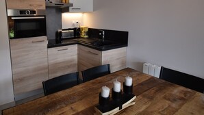 Una cocina moderna con una mesa de madera, cuatro velas y una cafetera.