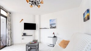 Een moderne woonkamer met een bank, een bijzettafeltje, een televisie en kunstwerken aan de muur.