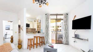 Een moderne woonkamer met een bank, een bijzettafeltje, een televisie en een balkon met uitzicht.