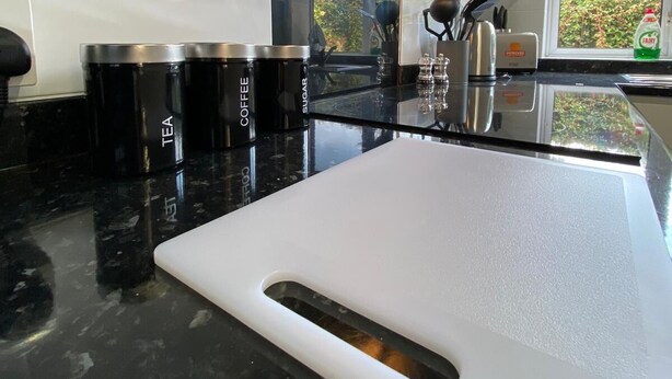 A modern kitchen with black countertops, stainless steel appliances, and a large window offering a view of greenery. - Reading 3 Bedroom apartment (Reading)