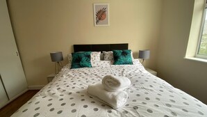 A neatly made bed with a polka dot bedspread, two teal pillows, and a rolled towel on the bed. - Reading 3 Bedroom apartment (Reading)