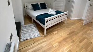 A small, clean bedroom with a single bed, white walls, and a wooden floor. - Modern 1 Bed Apartment (Reading)