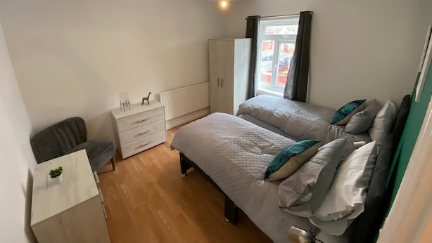 A bedroom with a bed, a wardrobe, a desk, and a window. - 3 Bedroom Apartment (Reading)
