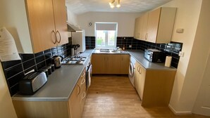 A modern kitchen with wooden cabinets, a gas stove, a built-in oven, a microwave, and a sink. - 3 Bedroom Apartment (Reading)