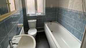 A bathroom with a bathtub, a sink, and a toilet. - 3 Bedroom Apartment (Reading)