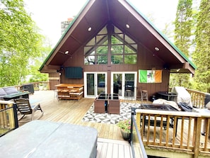 A wooden deck with a dining area, bar, and outdoor seating. - The Sacandaga Lakeside Escape - NEWLY RENOVATED 2024!  (Gloversville)