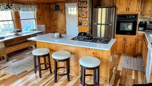 Una cucina con isola centrale, mobili impiallacciati in legno, un frigorifero e un piano cottura.