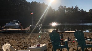 Una vista sul lago con un pontile, una barca e un tavolo da picnic con sedie.
