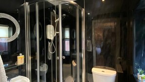 Een moderne badkamer met een douchecabine van glas, een toilet, een wastafel en een spiegel.