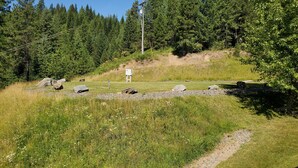Un campo cubierto de césped con un letrero blanco, rocas y un sendero.