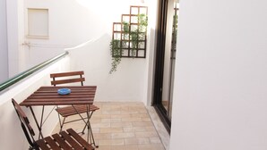 A small outdoor patio with a wooden table and chairs, a blue bowl, and a tiled floor. - Old Town Apartments 2D (Albufeira)