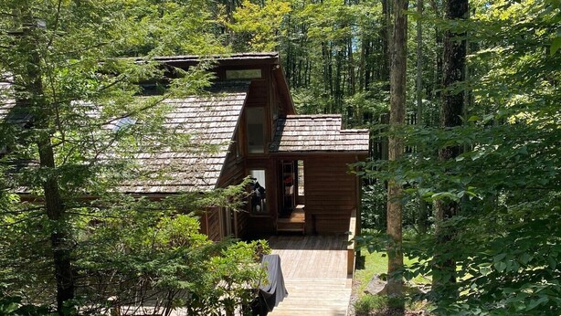 A wooden cabin with a sloped roof, a wooden deck, and a small porch. - Cozy Cabin Getaway - Convenient to 4 Ski Areas, Hiking and Mountain Bike Trails (Davis)