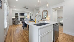 Una cocina moderna con una isla central, muebles blancos y lavavajillas.