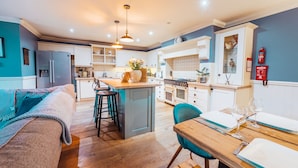 Una cocina moderna con una isla central, taburetes de bar y un comedor con una mesa para dos.