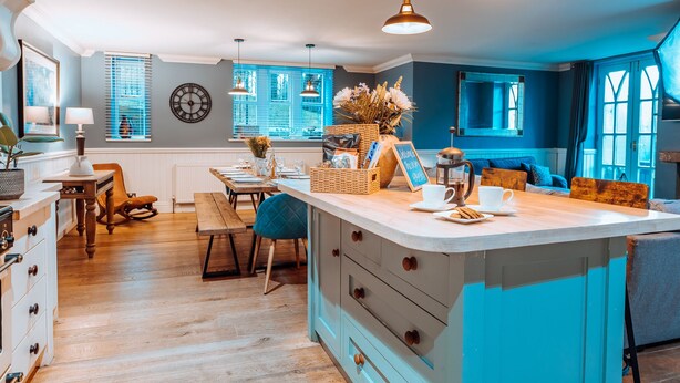 Una cocina moderna con una isla central, piso de madera e iluminación colgante.