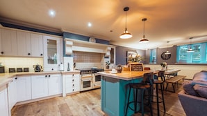 Una cocina moderna con armarios blancos, una isla verde azulada y taburetes de bar.