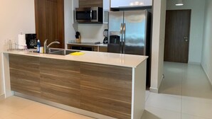 Une cuisine moderne dotée d’un îlot central, d’appareils électroménagers en acier inoxydable et de meubles de rangement en bois.