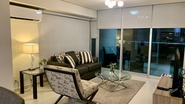 Un salon moderne comprenant un canapé, un fauteuil, une table basse et un meuble pour la télévision.