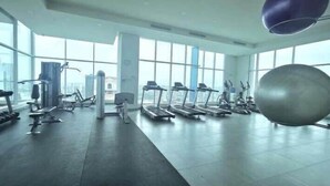 Une salle de sport équipée de tapis de course, de vélos elliptiques et d’un grand ballon de gymnastique.