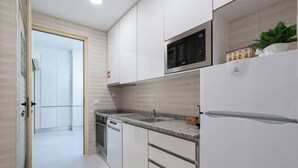 A modern kitchen with white cabinetry, a built-in microwave, and a refrigerator. - Anna´s Flats | Jardim do Morro by HostWise (Vila Nova de Gaia)